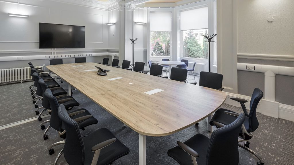 Large wood table with twenty black office chairs around