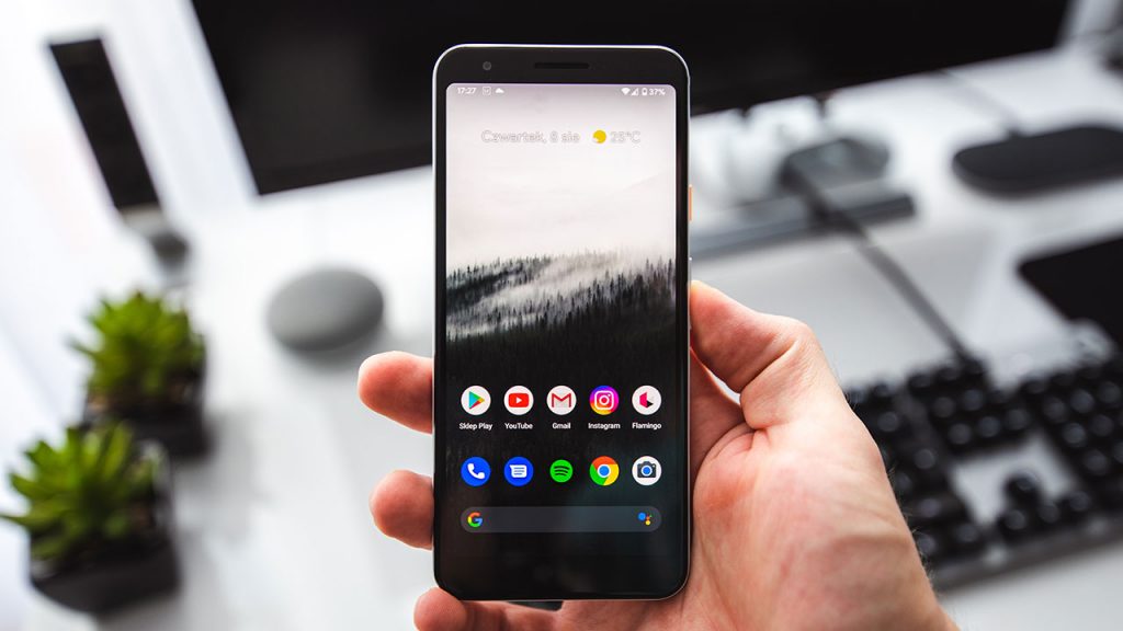 Hand holding a black phone, displaying colourful icons.