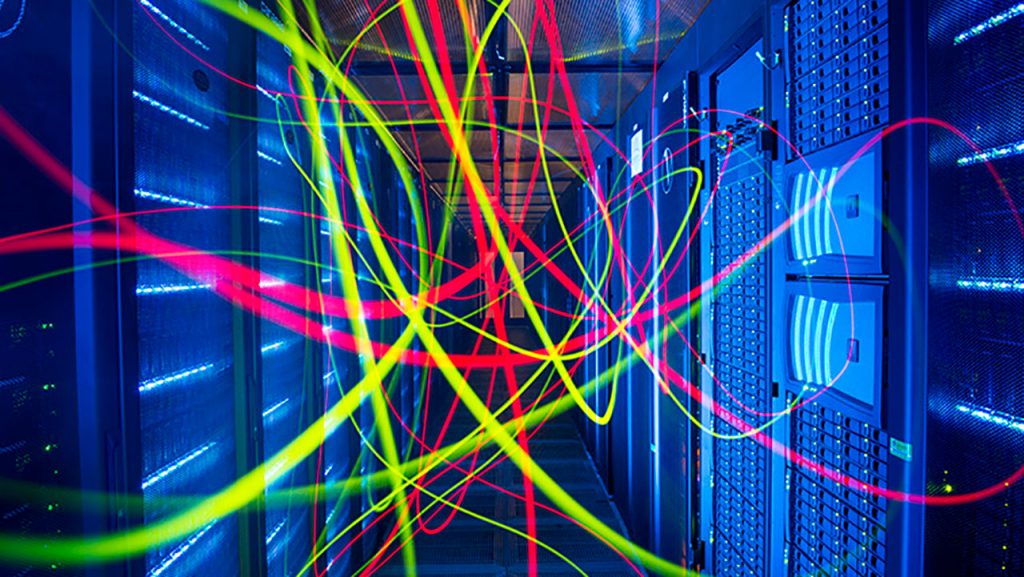 Brightly coloured light trails in a blue room full of computer servers
